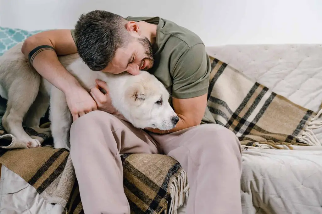 Man on couch snuggling dog